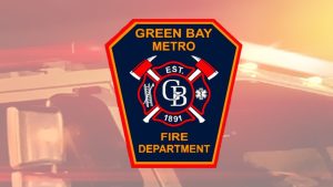 Green Bay Metro Fire logo over firetruck graphic background