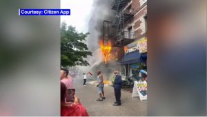 Fire shown on exterior of liquor store with citizen using fire extinguisher
