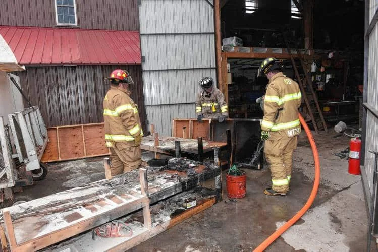 firefighters remove burnt materials from a workshop